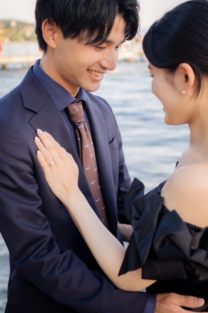 Zurich wedding Couple laughing face to face by the water, her hand and engagement ring resting on his lapel